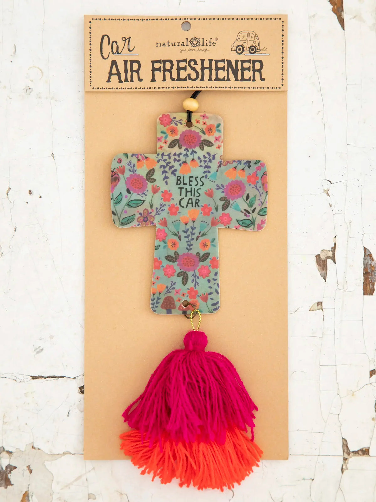 cross air freshener with pink and orange tassels with the words bless this car