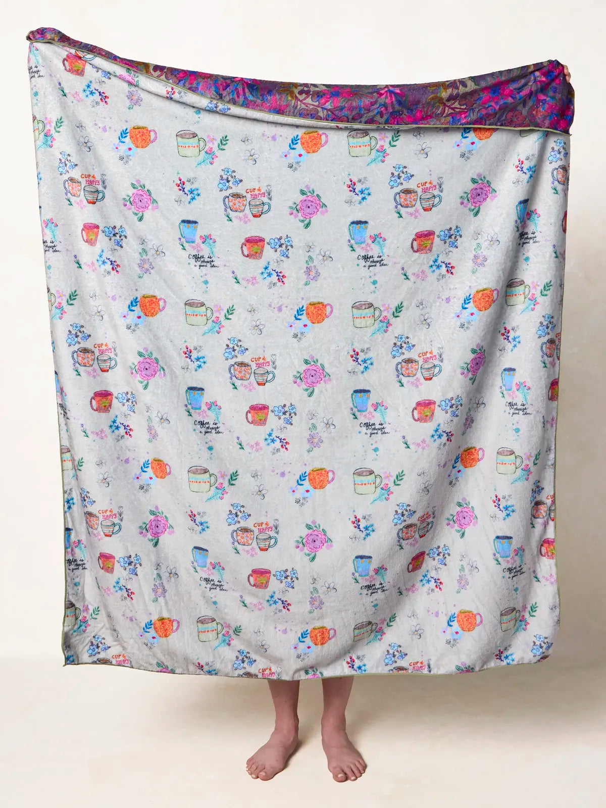 BLANKET WITH COFFEE CUPS AND FLOWERS ON IT ON A WHITE BACKGROUND