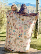 2 WOMEN HOLDING A BLANKET WITH HORSES, SWANS FLOWERS AND HORSE SHOES