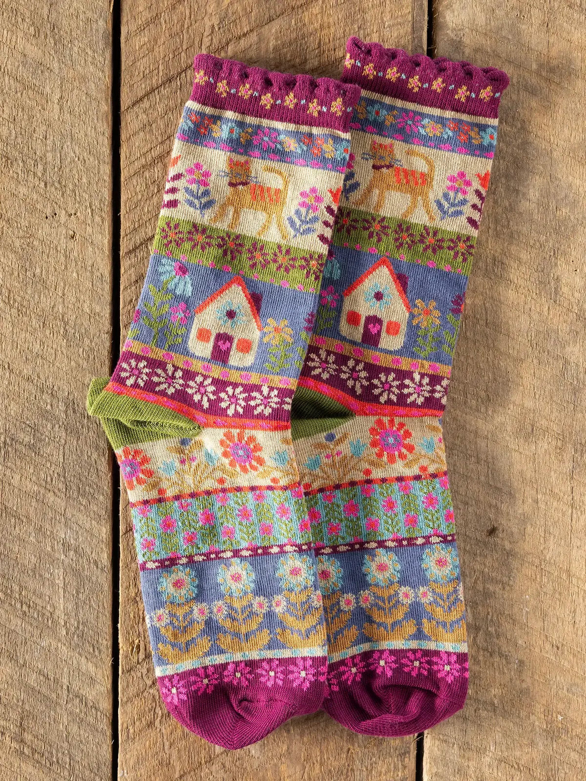 MULTI COLOR SOCKS WITH CAT AND HOUSE ON THEM ON WOODEN FLOOR