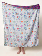 BLANKET WITH COFFEE CUPS AND FLOWERS ON IT ON A WHITE BACKGROUND