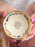 ROUND TRINKET BOWL WITH FLOWERS AND A GOLD EDGE WITH THE WORDS A SISTER IS A LITTLE BIT OF CHILDHOOD THAT CAN NEVER BE LOST